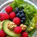 Plato colorido con frutos rojos, aguacate, nueces y verduras, simbolizando nutrición anti-inflamatoria